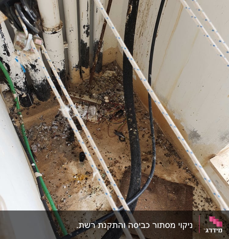 חבלים, צינורות ולכלוך על רצפה בפינת מבנה